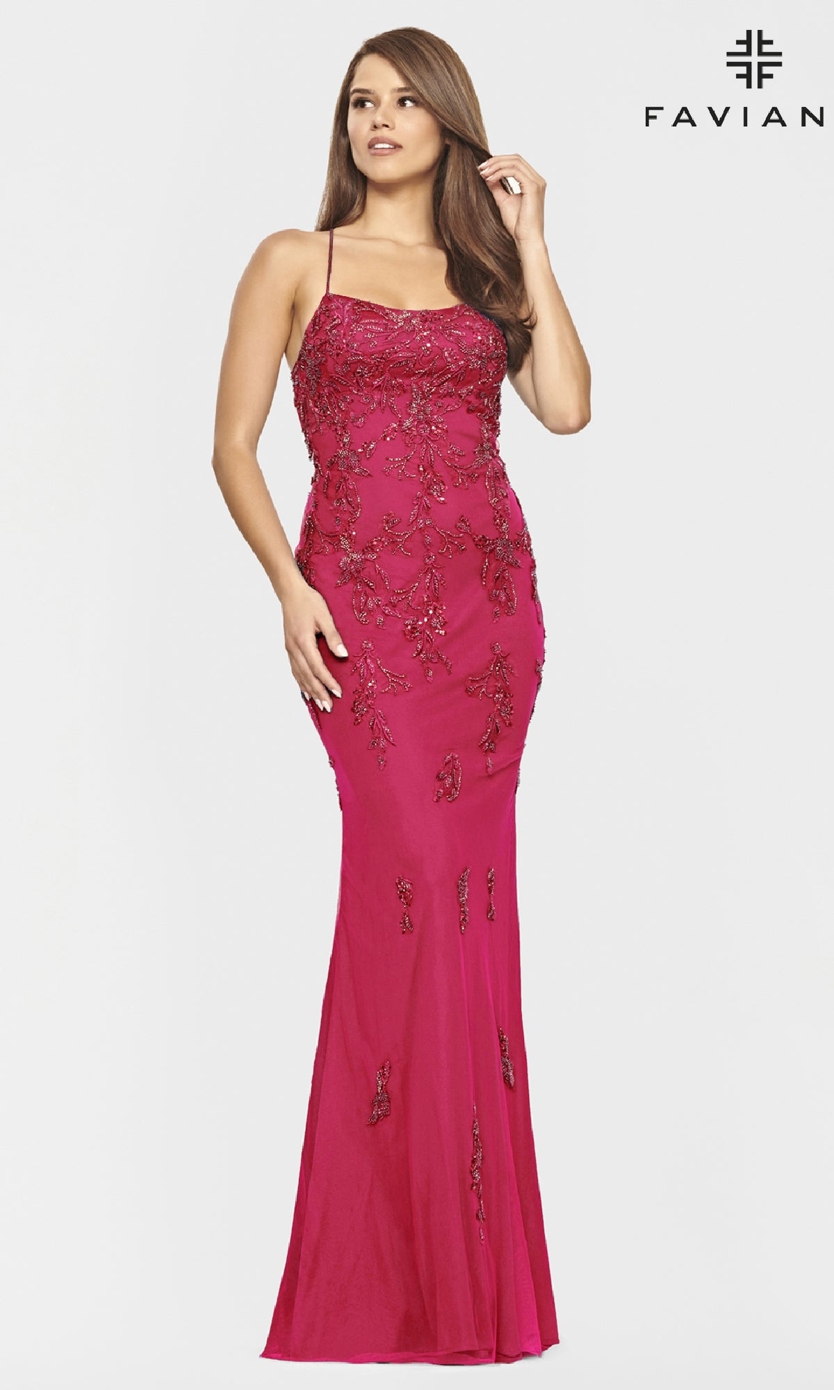 Woman wearing a fitted, floor-length yellow Faviana prom dress with thin straps and open back, standing against a plain white background with the